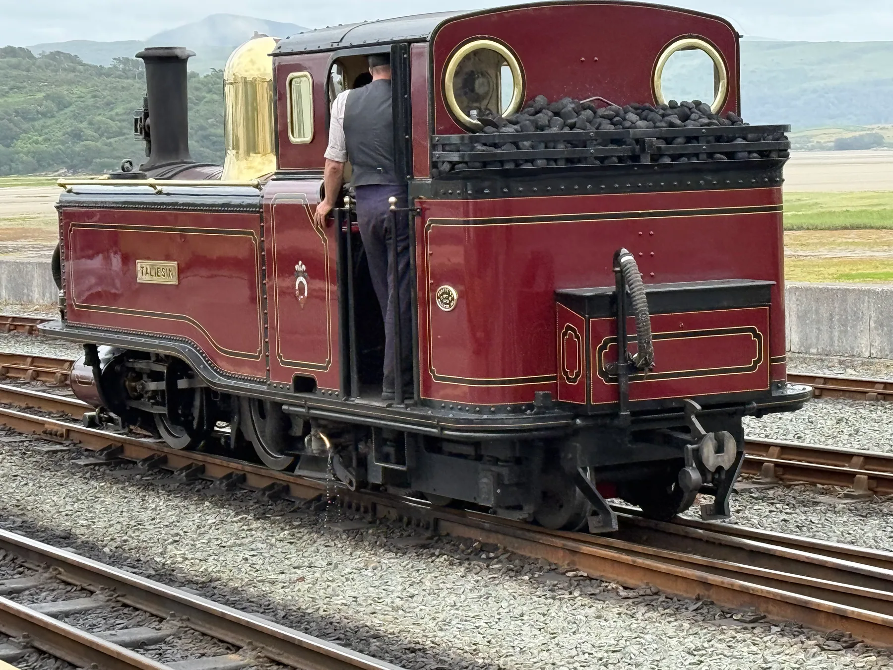 Full-size red Taliesin locomotive standing at a station platform