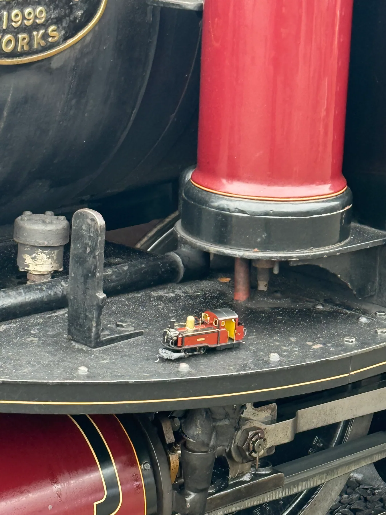 Tiny Taliesin model positioned beside the full-size locomotive's red chimney
