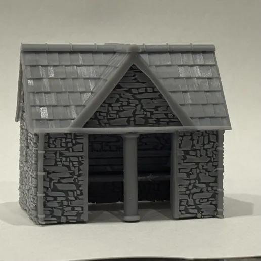 Front view of the printed dressed stone bus stop with a slate roof, stone gable and open front divided by a central column.