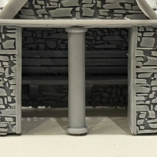 Close-up of the printed bus stop entrance showing the central column, stone texture and bench inside the shelter.