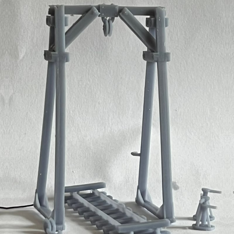 Unpainted print of the hoist assembled on its track base, showing the braced A-frames, pulley block and an axle jack.