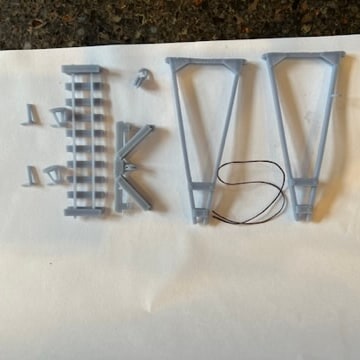 Printed hoist parts laid out flat: two A-frames, the track base, cross braces, pulley block and axle jacks.