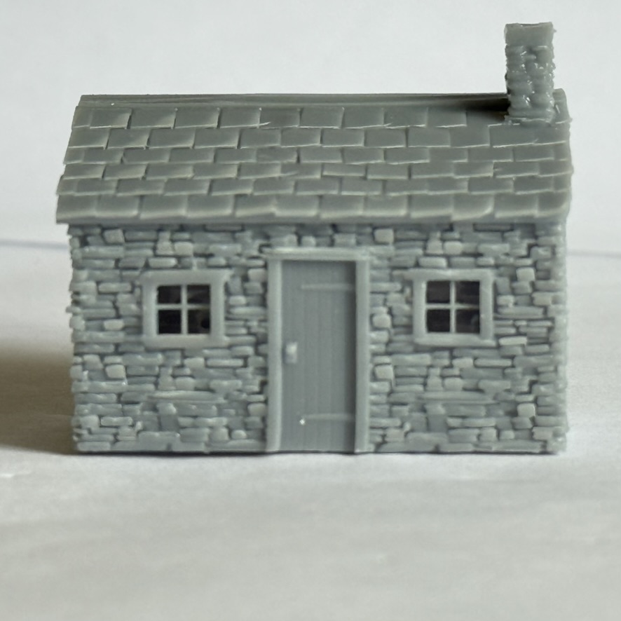 Front elevation of the printed stone lineside hut with central door, two windows, slate roof and chimney.