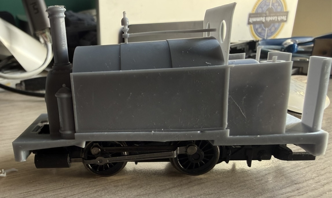 Unpainted grey resin print of the saddle tank locomotive body sitting on its chassis, showing the tank, chimney and cab.