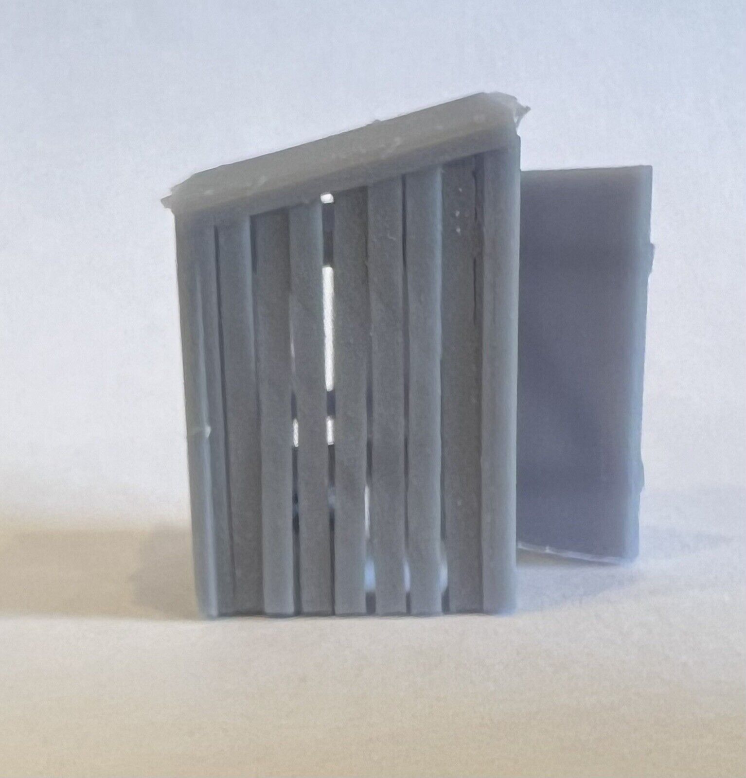 Side view of the printed privy showing the vertical plank walls, sloping roof and open door.