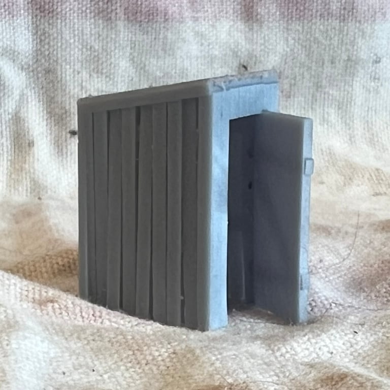 Three-quarter view of the printed privy with its plank walls and the door standing open.