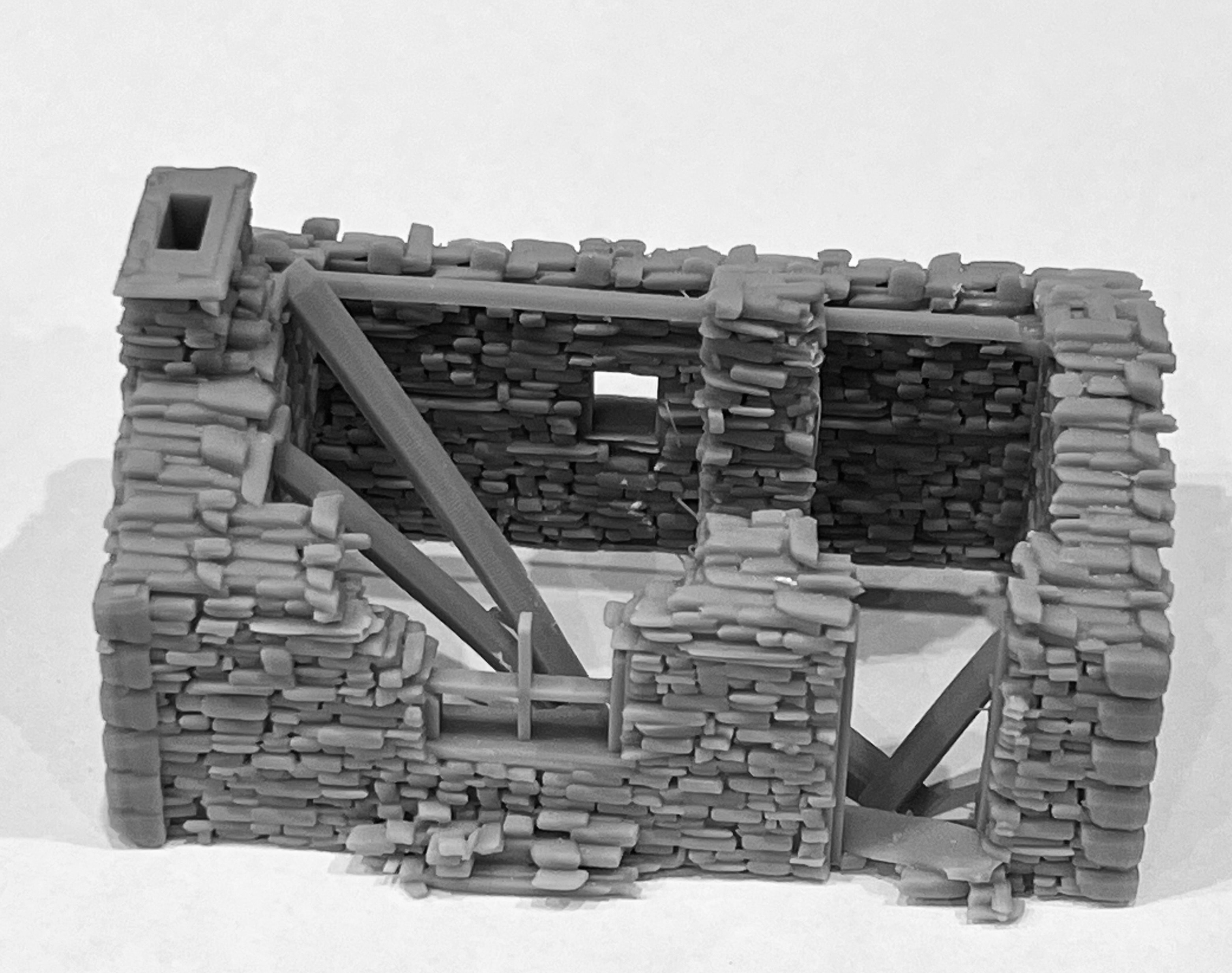 Three-quarter view of the ruined cottage model showing collapsed roof timbers and stone wall detail