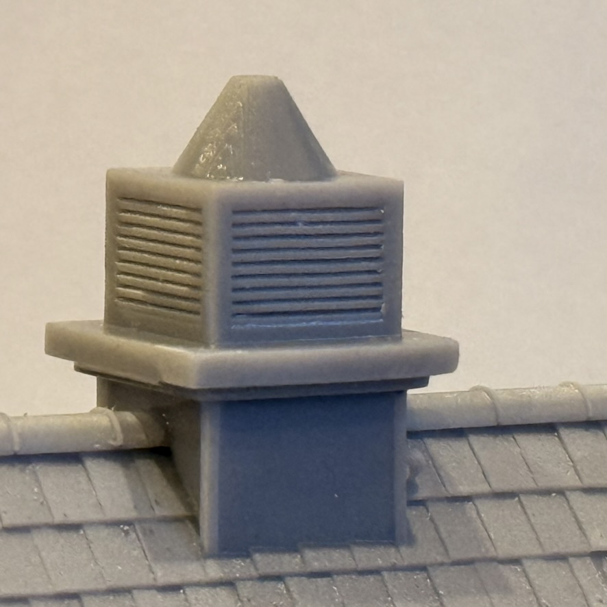 Close-up of the louvred ventilator with its pointed cap sitting on the slate roof ridge.