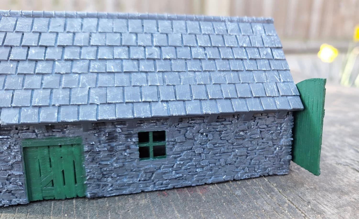 Side of the painted smaller loco shed showing the slate roof, window and green side door