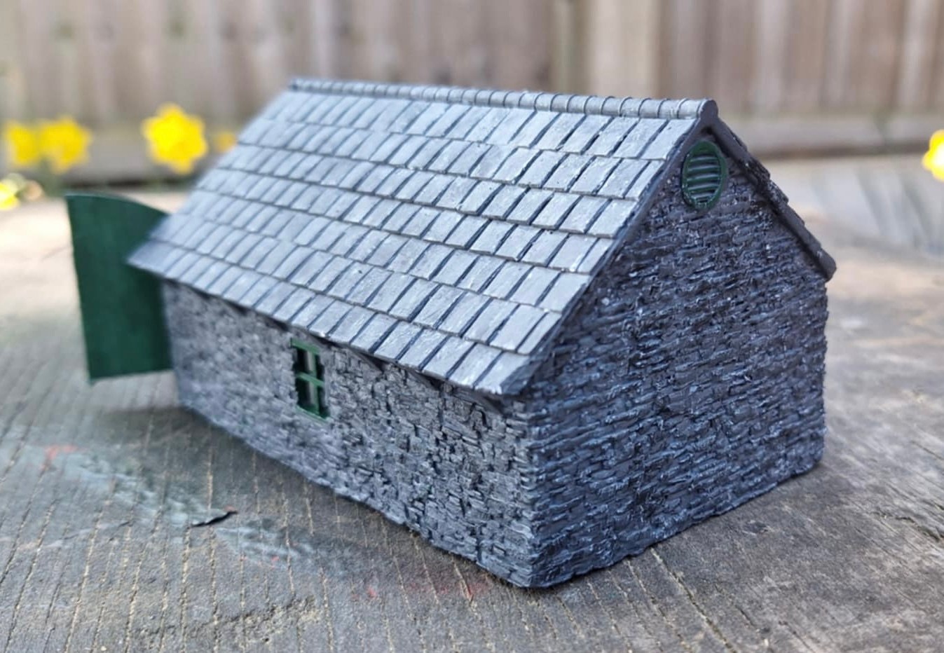 Rear three-quarter view of the painted smaller loco shed showing its stone walls and slate roof