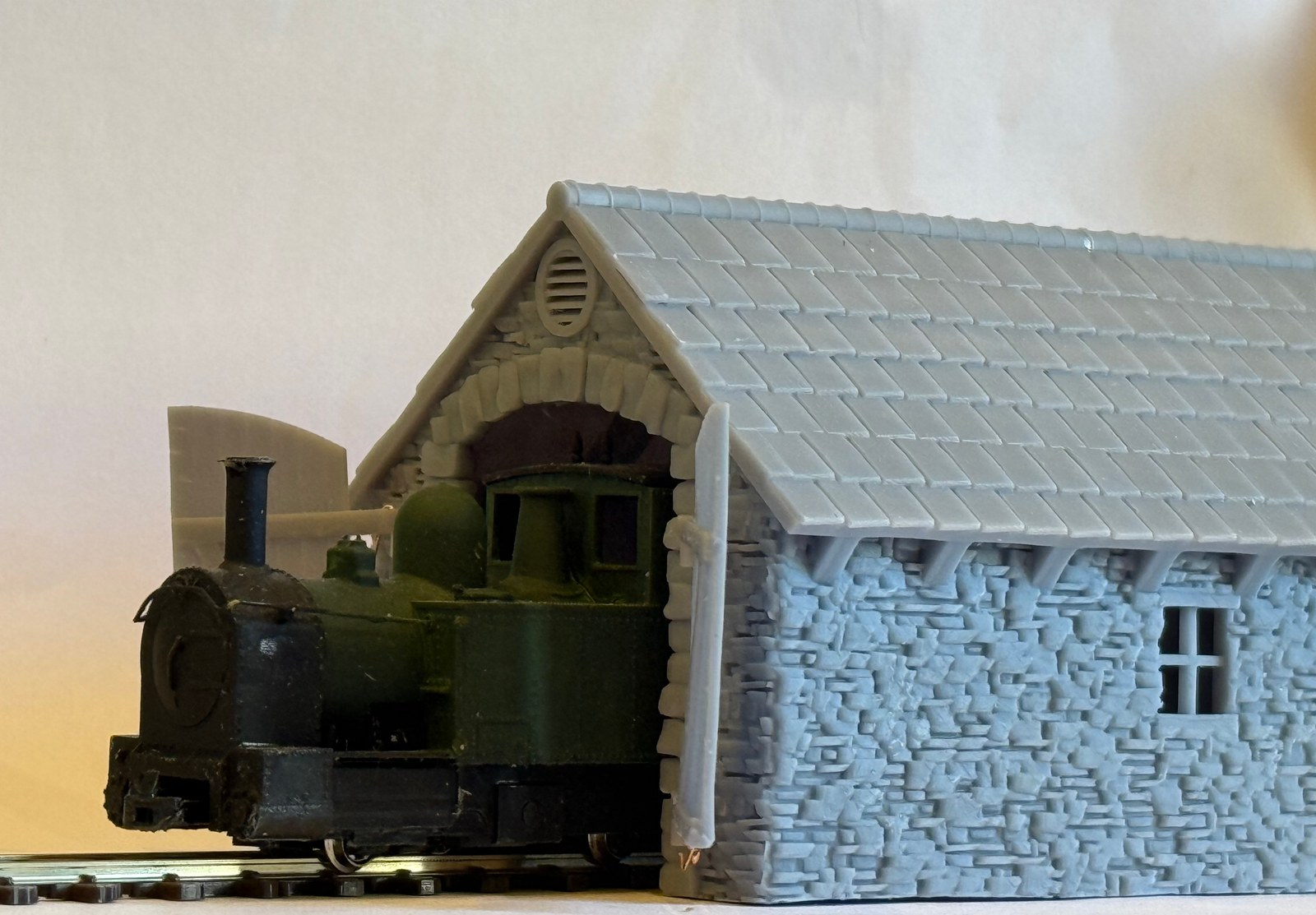Unpainted smaller 009 loco shed with a narrow gauge locomotive at the open entrance